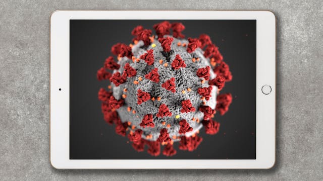 Photograph of an iPad resting on a concrete textured surface. On the screen of the iPad is a computer rendered illustration of virus SARS-CoV-2 as a light grey floating orb with protruding red spikes.  