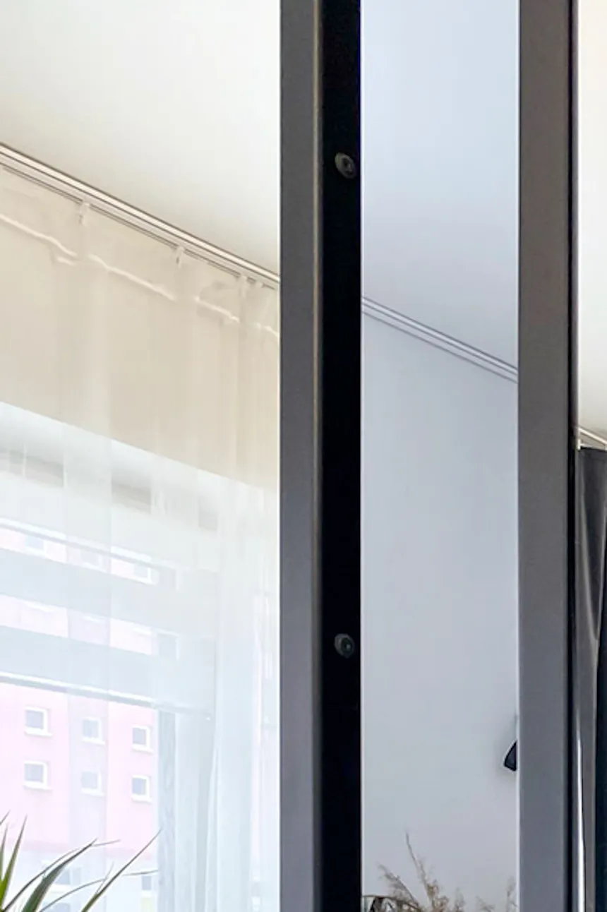 Poignée en métal montée sur une porte avec un miroir dans un cadre en métal