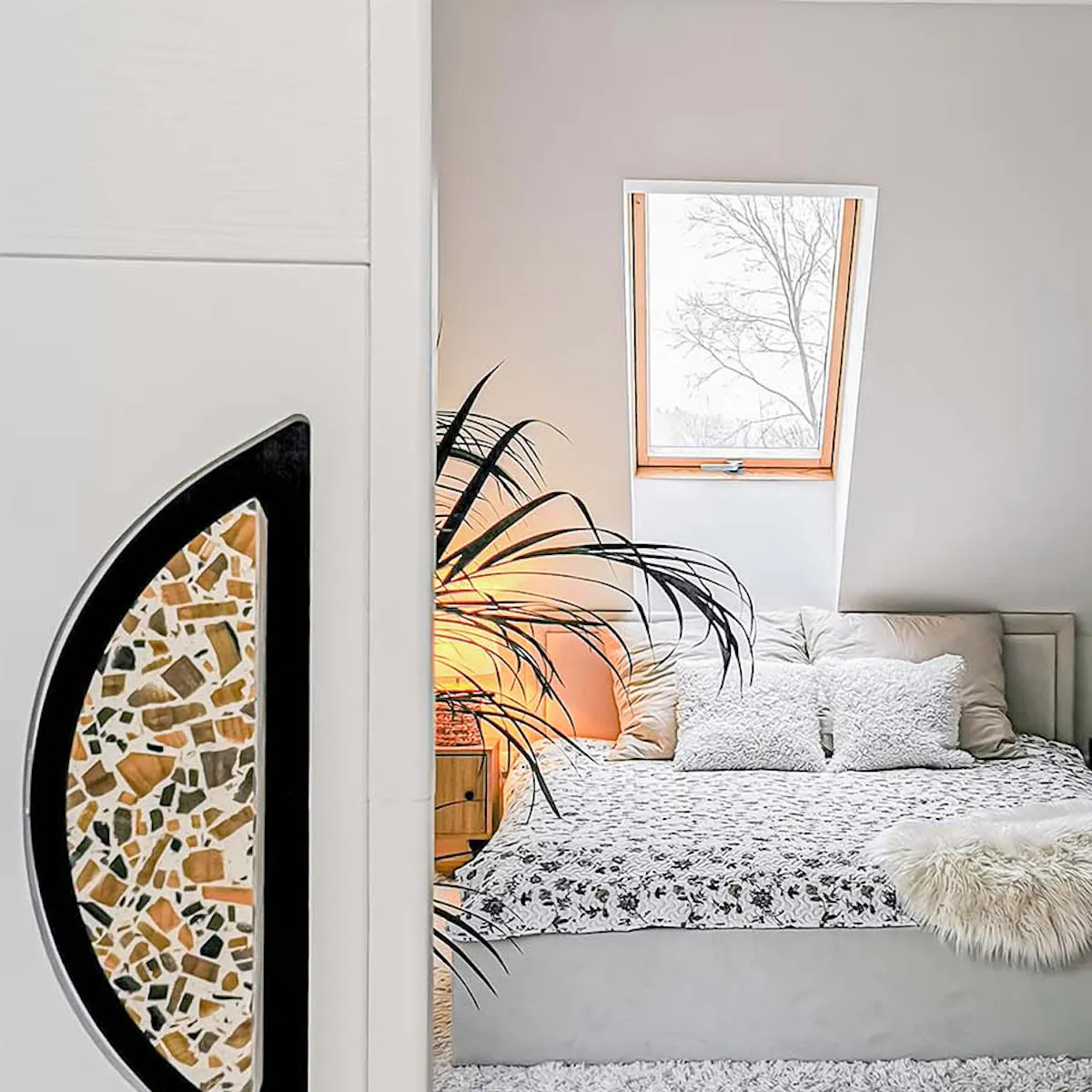 une porte entrouverte dévoilant une chambre avec un lit capitonné aux couleurs blanc et beige
