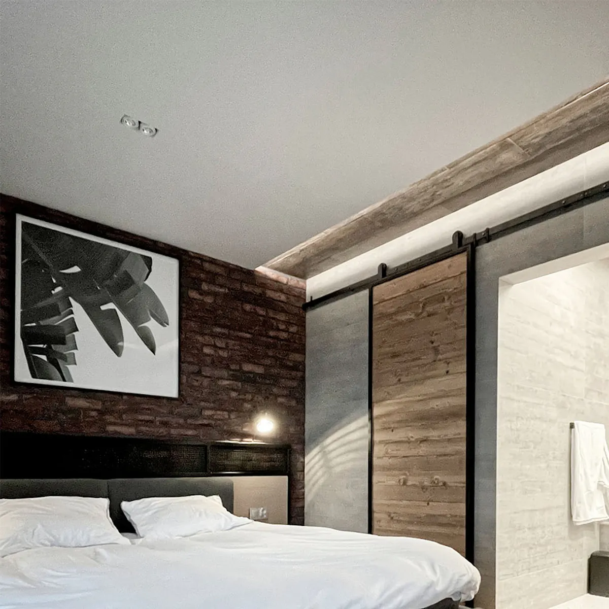 Sliding door to bathroom in industrial bedroom with red brick wall