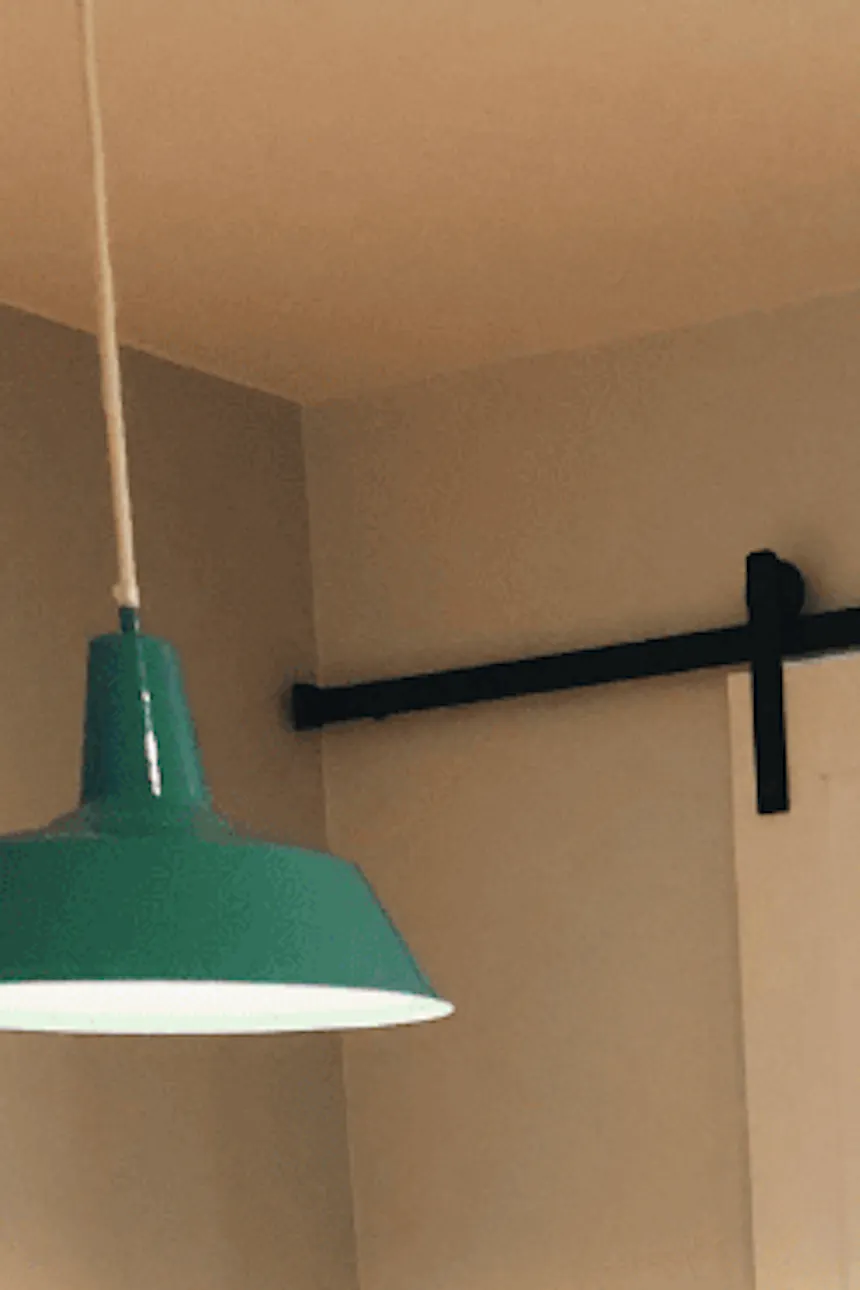 un canapé émeraude et des portes coulissantes blanches dans un salon décoré dans un style scandinave