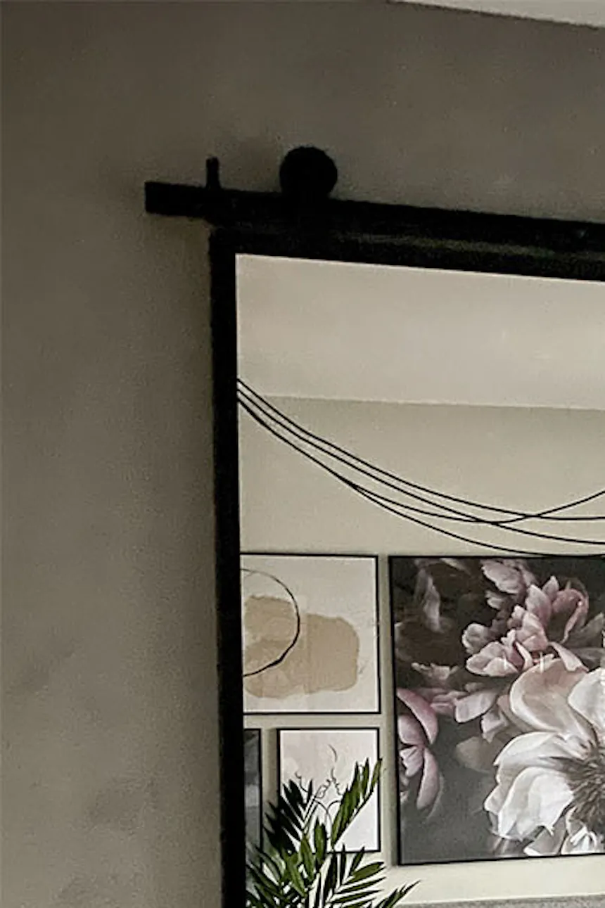 Sliding door with mirror in metal frame on gray wall in loft-style bedroom with gray tones