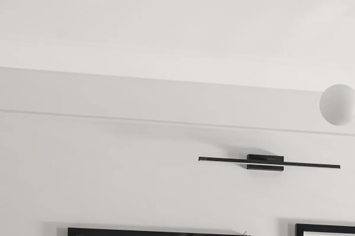 Abstract paintings in black frames, light wall in living room, metal lamp