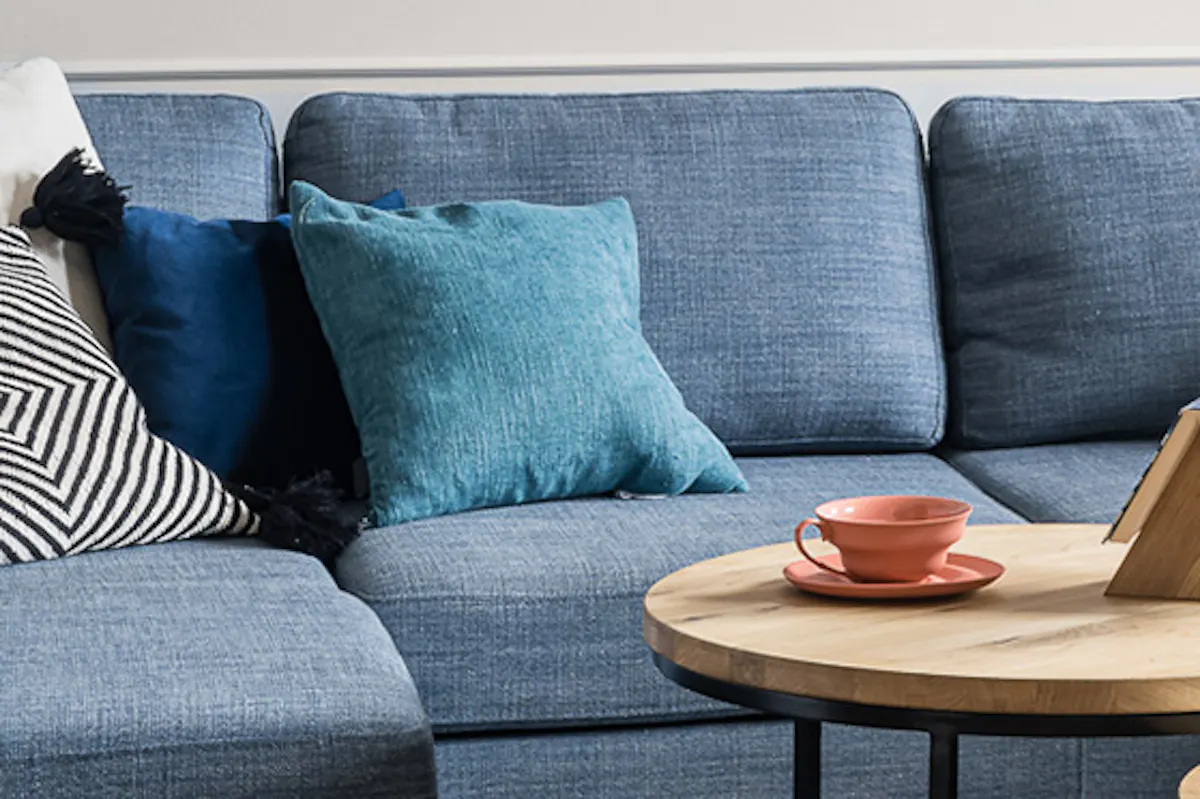 Round coffee tables, large blue denim sofa, colorful pillows, geometric patterned rug, living room seating area