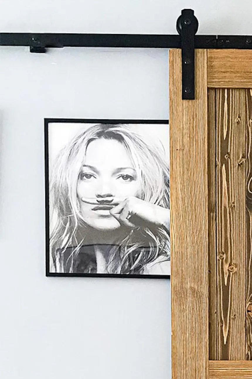 sliding doors in a small apartment, black and white posters on the wall, decorative clock, wooden sliding door with a black handle