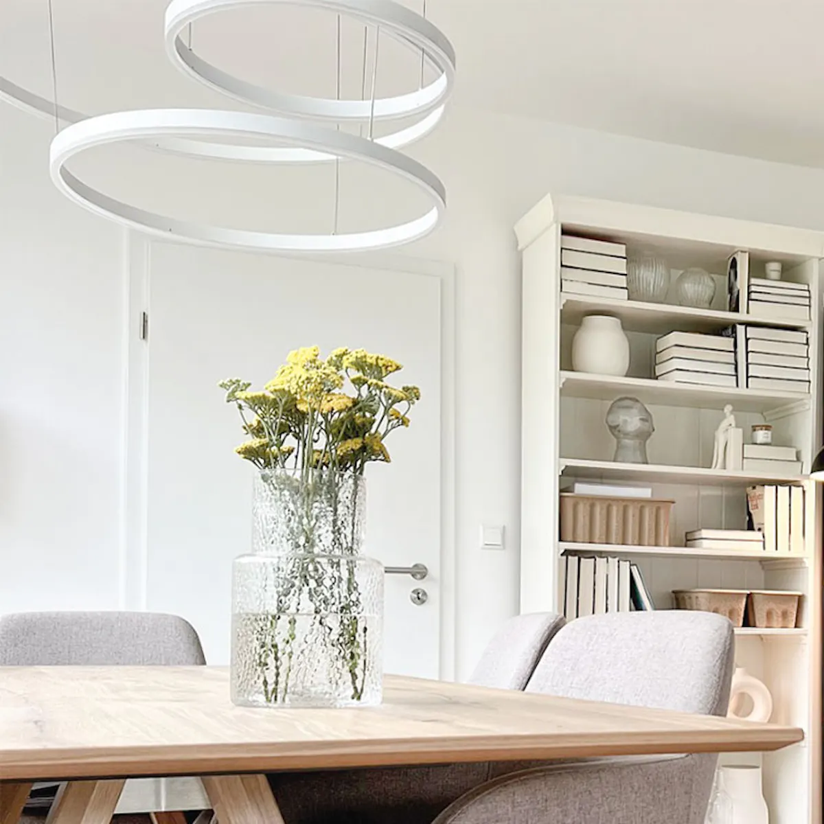 Nordic style wooden dining table, modern lamp above, dining room connected to kitchen through metal glass sliding door