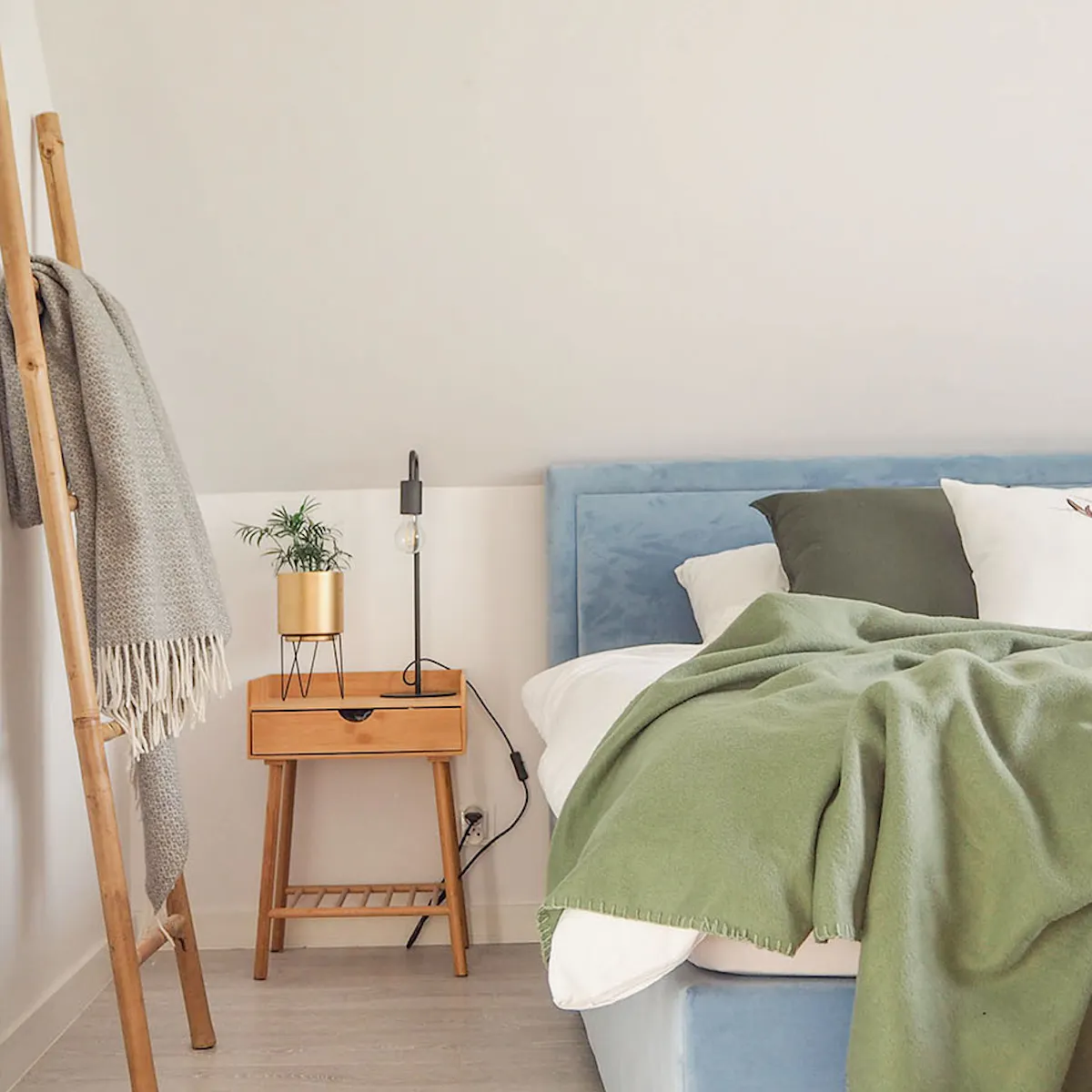 Lit capitonné bleu et accessoires en bois dans une petite chambre mansardée