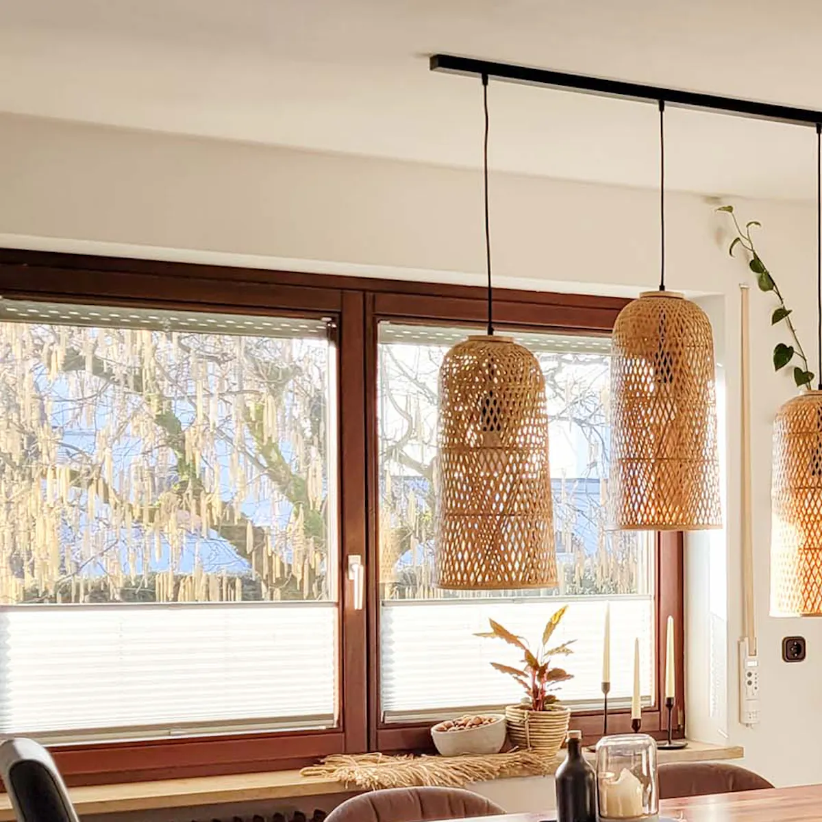 lampes en rotin suspendues au-dessus d'une table en bois près de la fenêtre