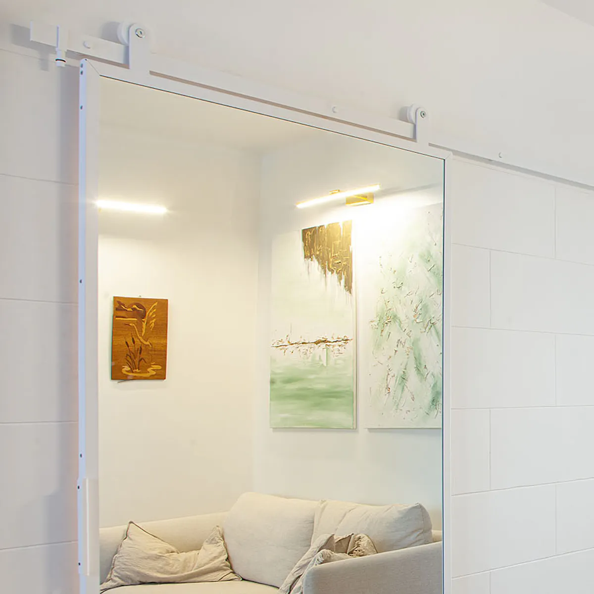 porte coulissante en métal blanc avec miroir dans le salon avec canapé crème clair