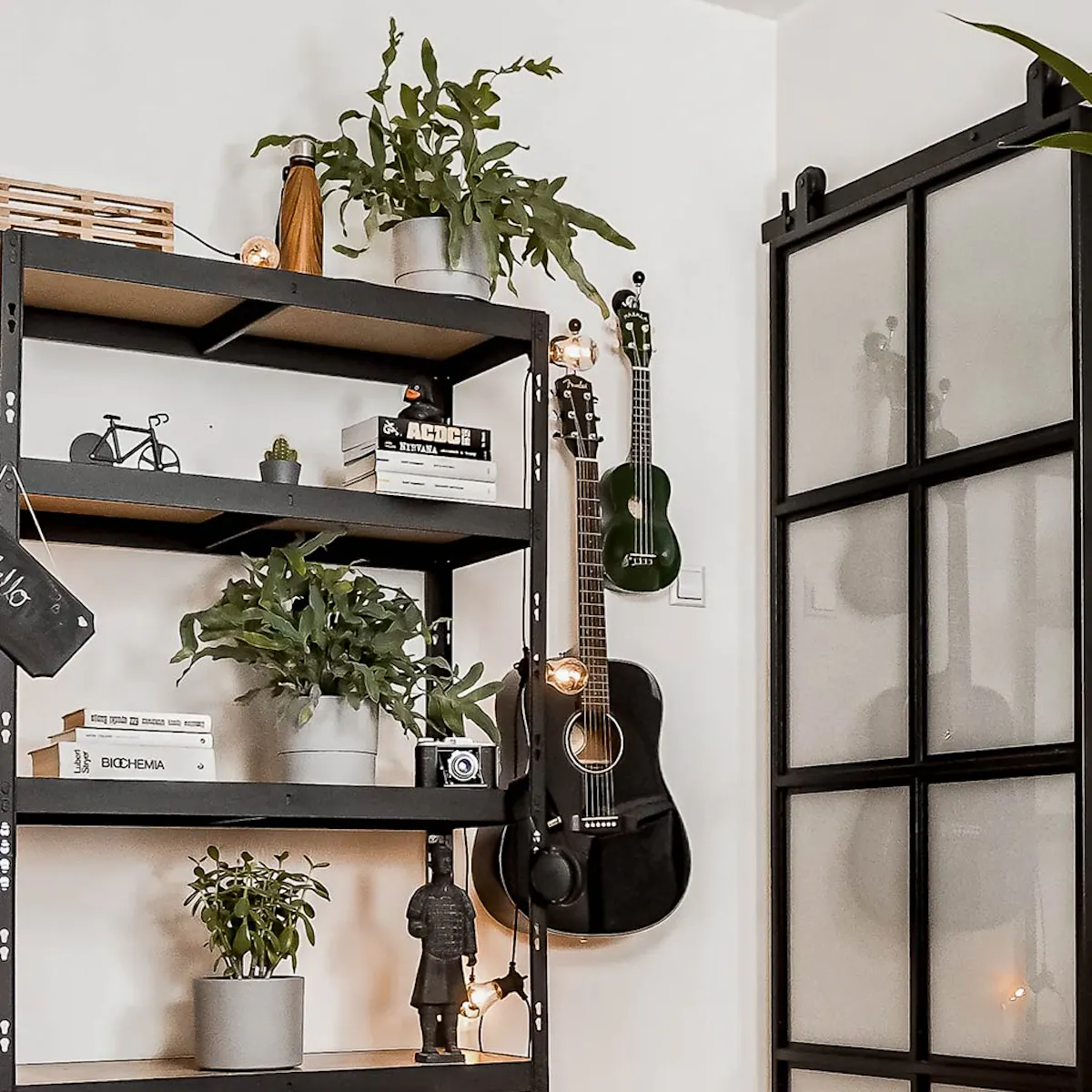 Student room setup, metal sliding door with glass, loft style, loft-style bookcase, plants, vintage chair, white wall and black decorations