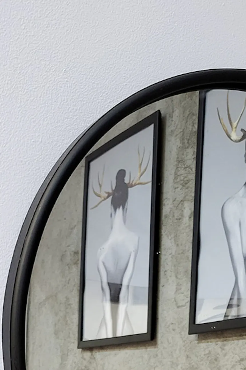 round mirror in a black frame, with a small shelf