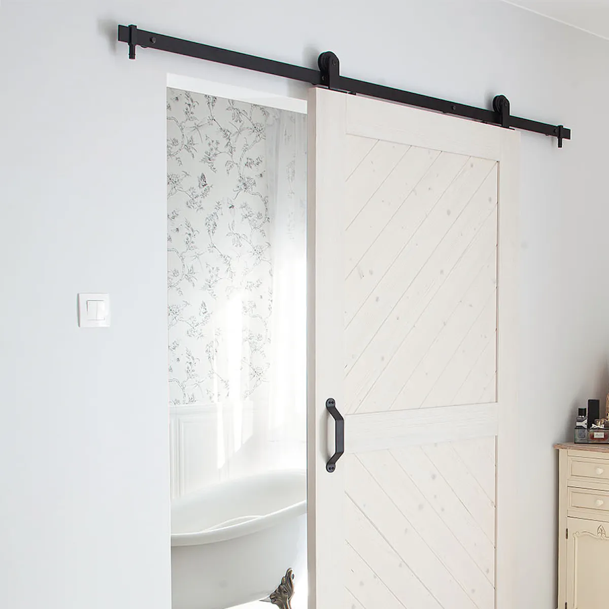 white wooden sliding door separating the bathroom from the Provence-style bedroom