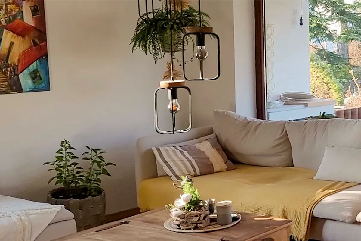 un canapé crème, une table coffre et des chaises en rotin dans le salon