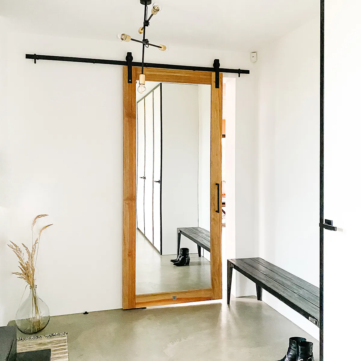 Mirror door in entryway, large mirror in wooden frame, industrial lamp, microcement floor, entryway bench