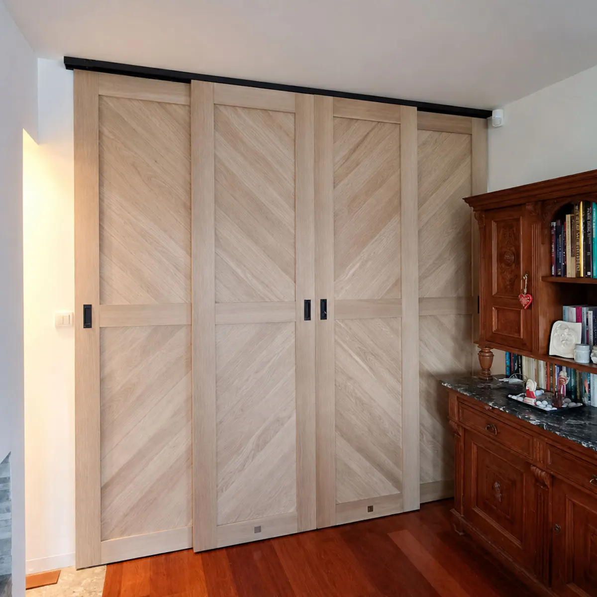 Closed four-panel bypass sliding doors with light wood herringbone panels forming room divider