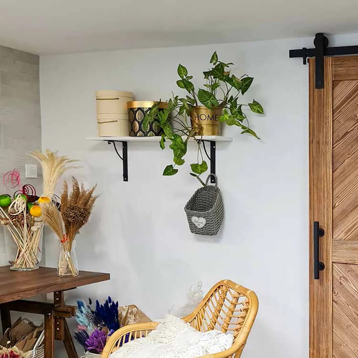 solid wood sliding door, black sliding system, wicker chair on metal legs, dried flower decorations, light walls and dark floor in a Scandinavian interior