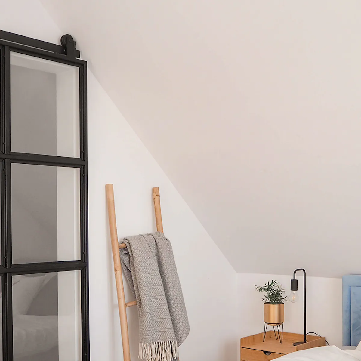 un lit sous un toit en pente dans le mansardée dans une chambre avec un petit dressing