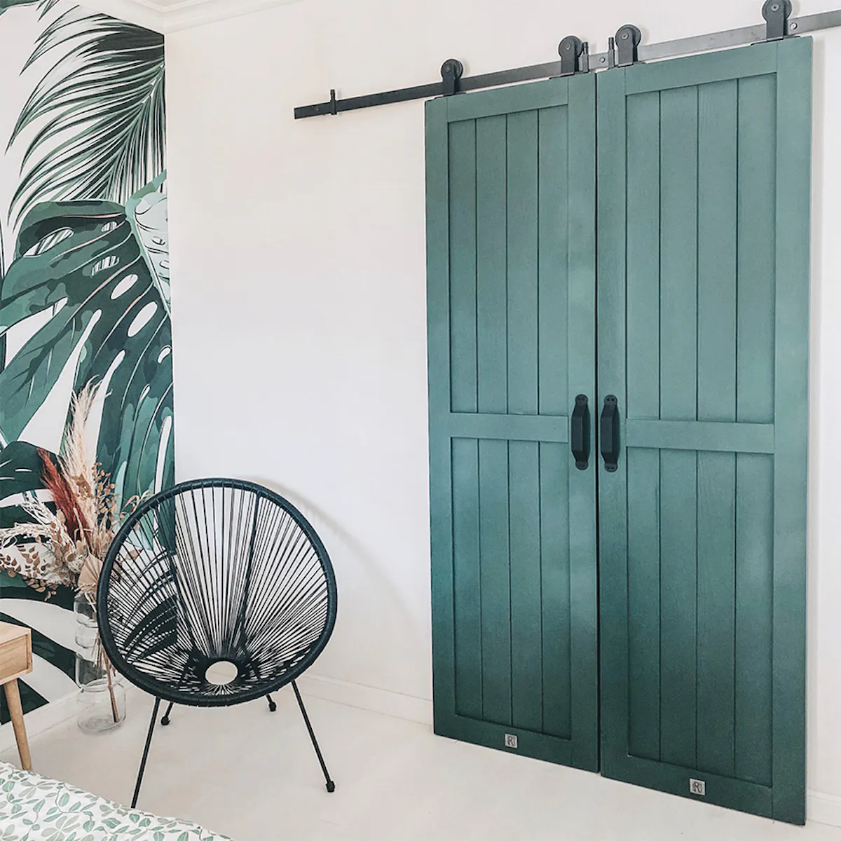 green doors, walk-in closet door, sliding door, black sliding door system, black openwork armchair, solid wood door, white and green in the bedroom, botanical wallpaper, plant wallpaper