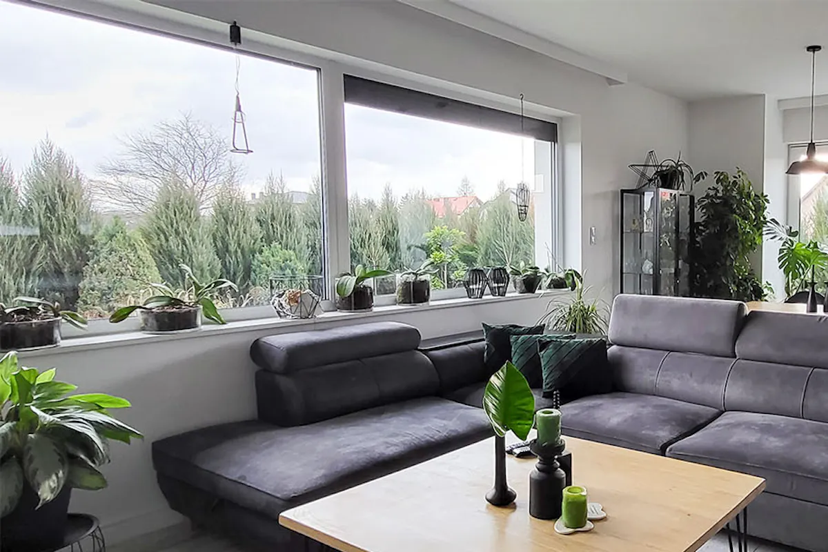 un salon avec un canapé gris et une table basse carrée en bois dans un agencement gris et noir