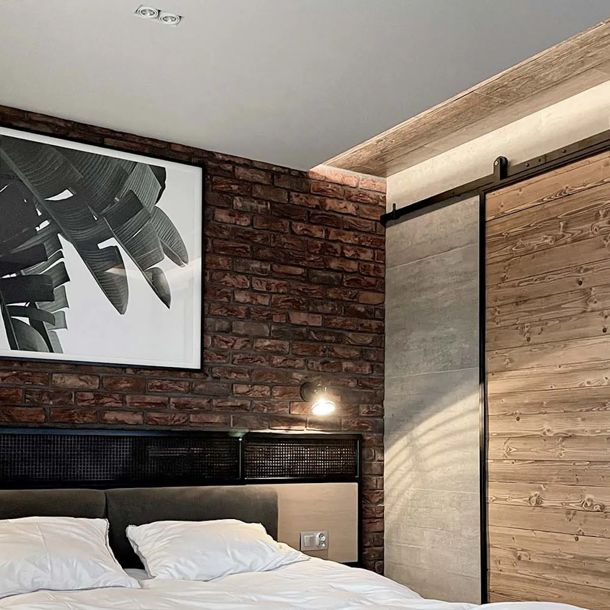 Industrial bedroom with red brick wall and industrial sliding doors to bathroom