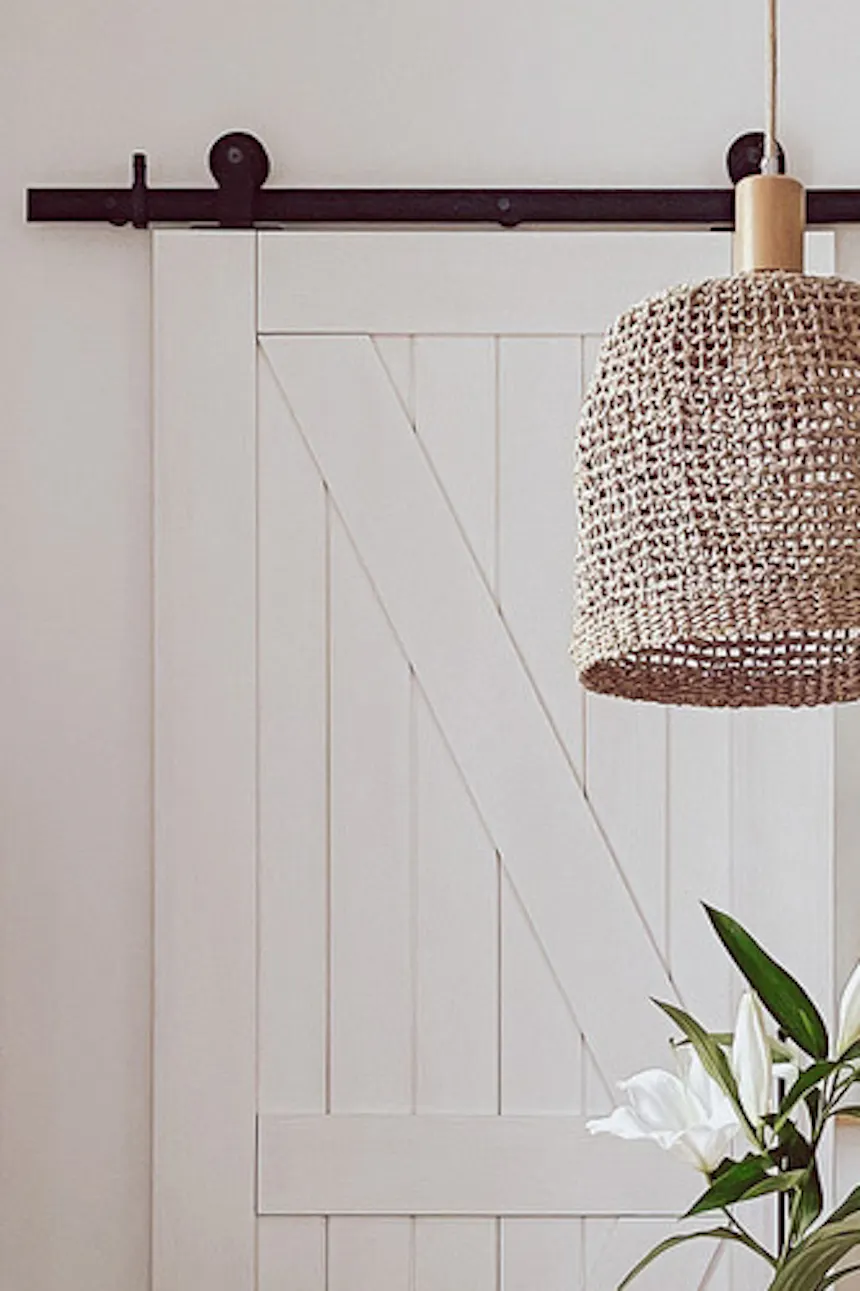 white chairs at the round table, boho style hanging lamp, white double sliding bedroom doors