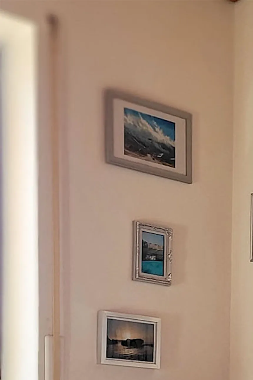 une chaise berçante en osier près d'un mur décoré d'une galerie de photos