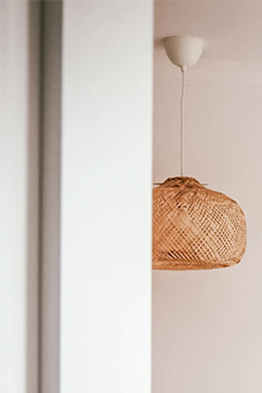 un couvre-lit beige, des coussins décoratifs et des suspensions ajourées dans une chambre de style bohème