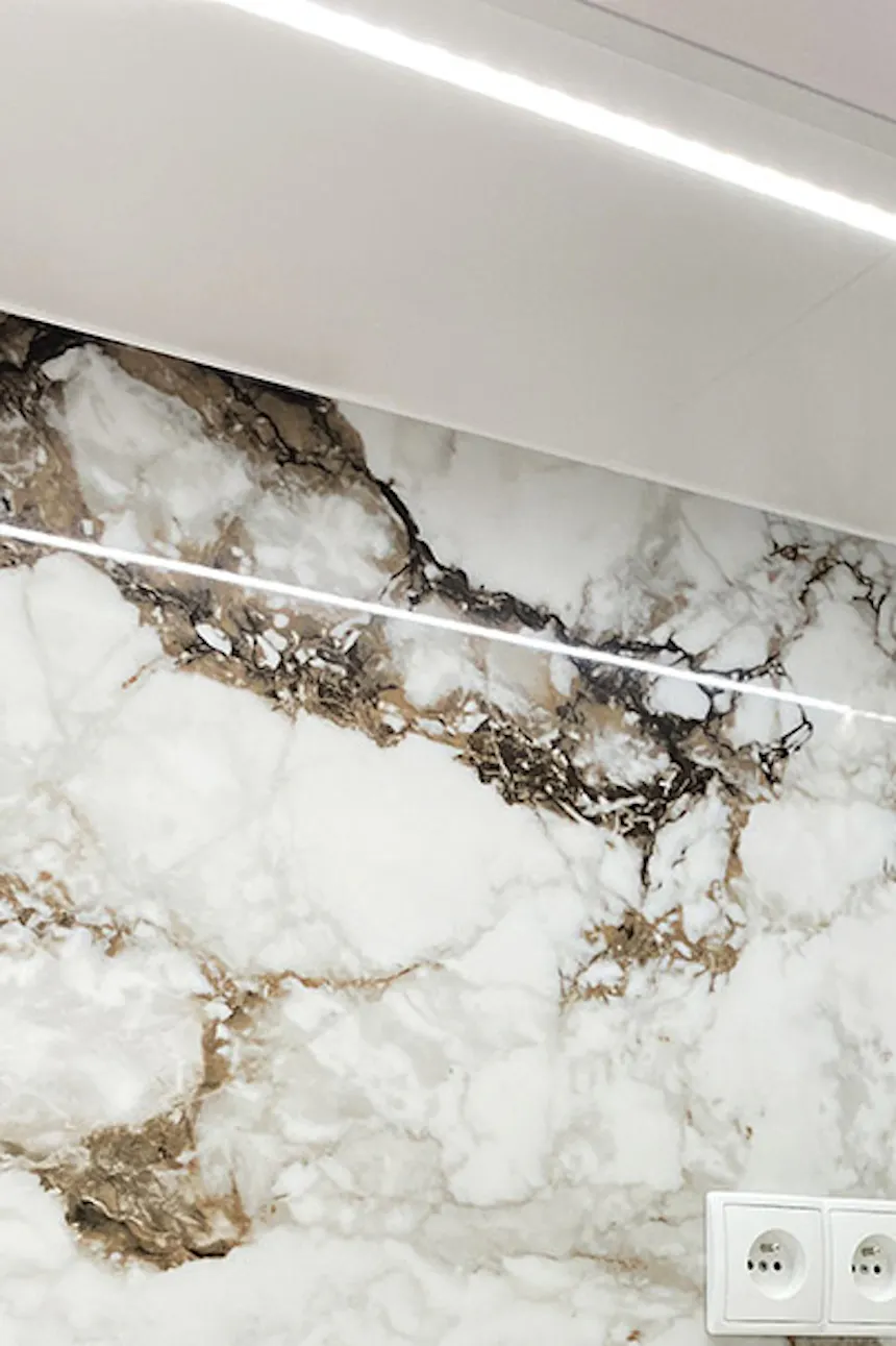 Stone-patterned tiles above kitchen counter, white cabinetry, modern apartment