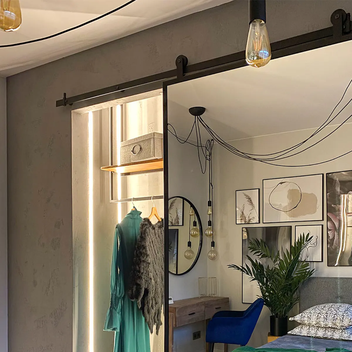 Open sliding mirror door showing small dressing room in niche beside gray-decorated bedroom