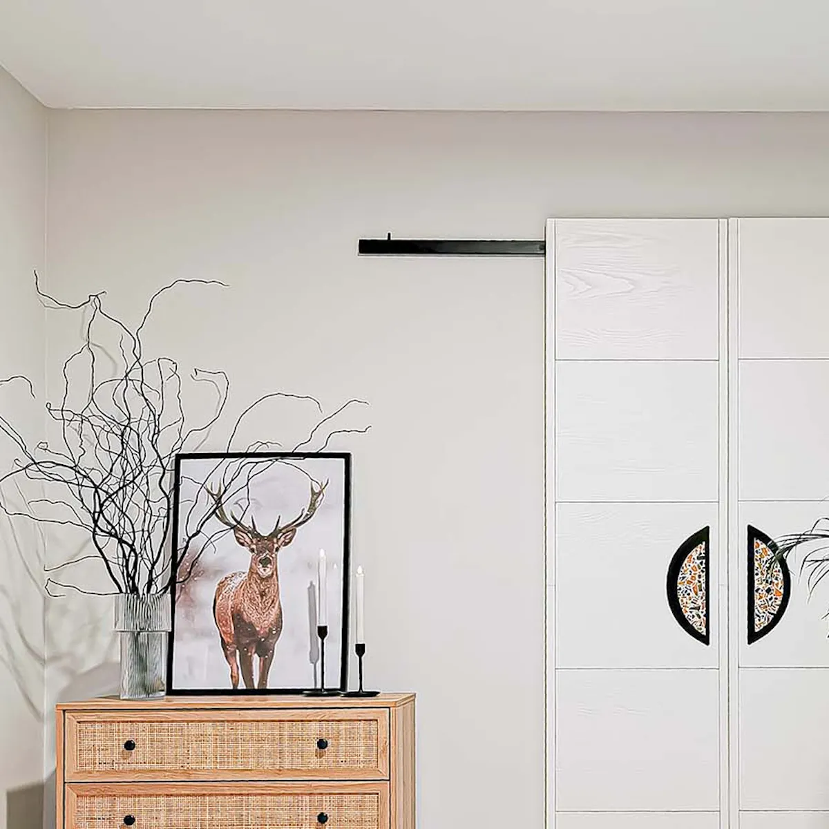 une commode avec des façades de tiroirs en rotin se tenant à côté de doubles portes coulissantes blanches dans un style minimaliste