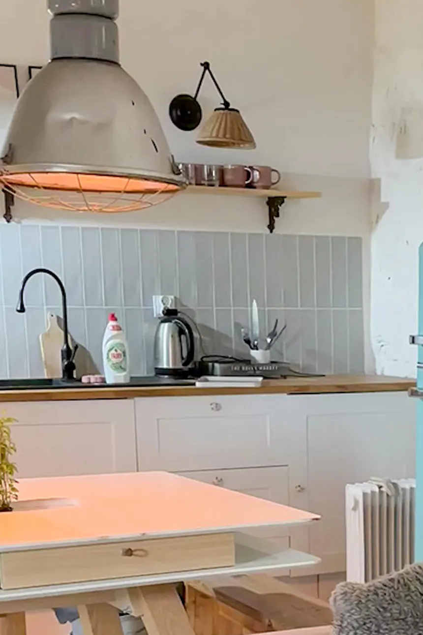 un canapé marron dans le salon et un réfrigérateur bleu dans la cuisine dans un design intérieur de style champêtre