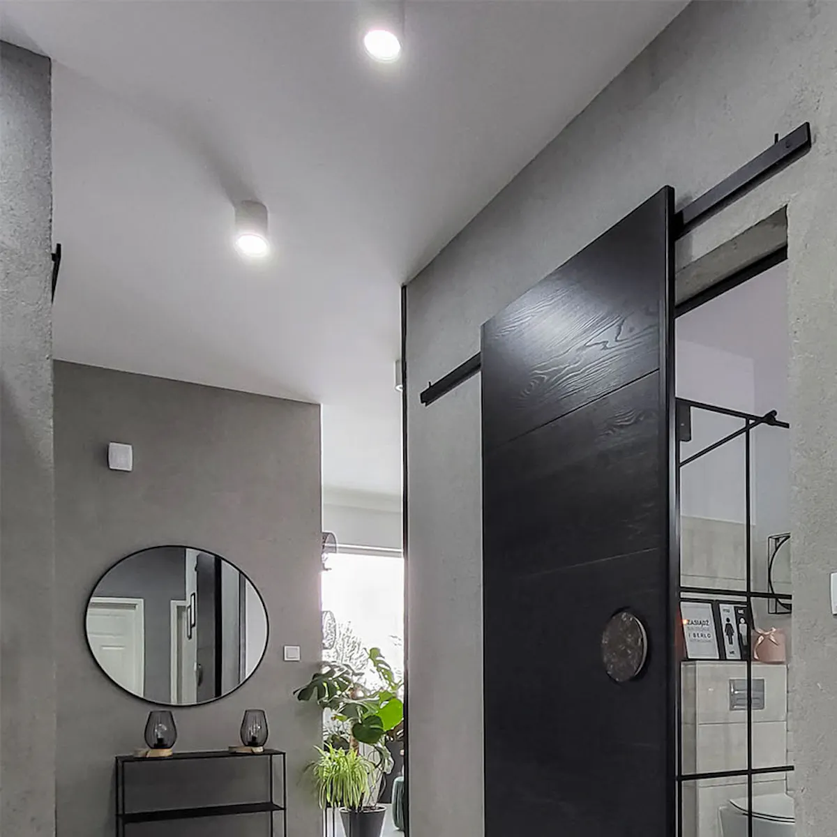 black sliding door in the entrance to the bathroom in the hallway with gray walls