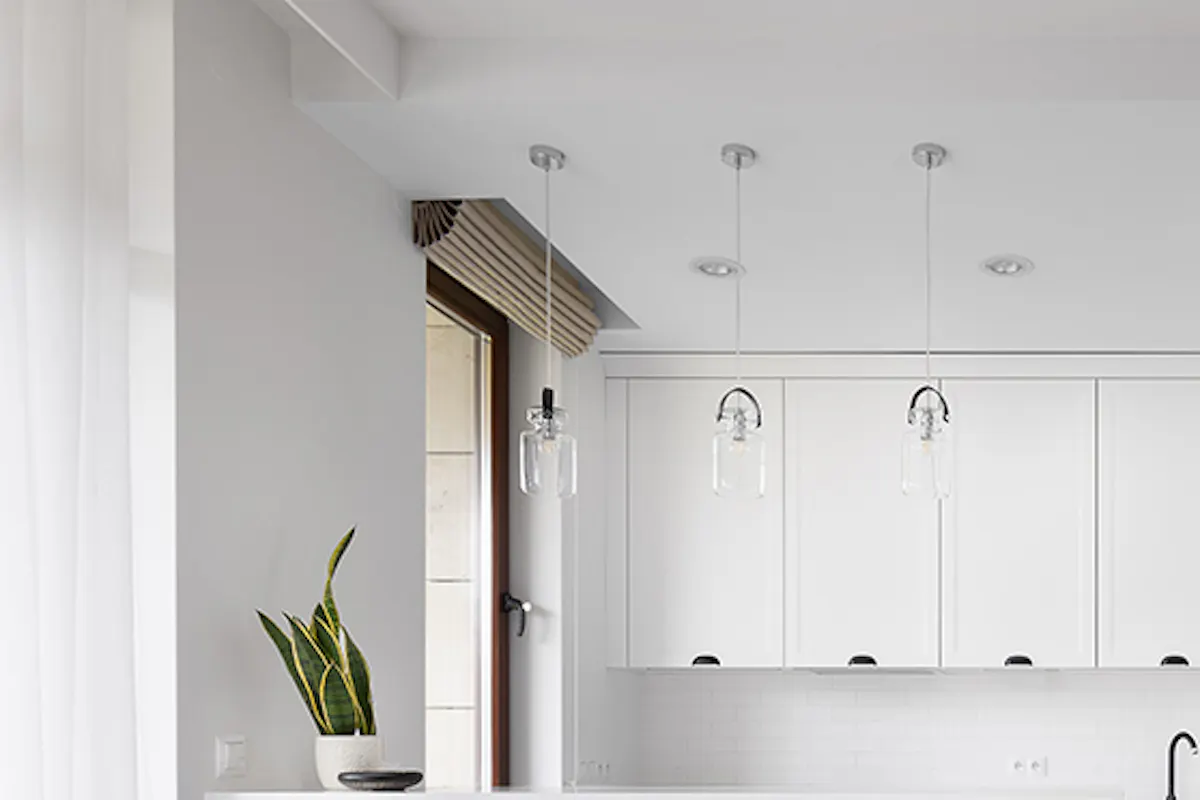 white kitchen with black accessories, white sliding door to utility room, blue accents in kitchen, industrial bar stool with bicycle pedals