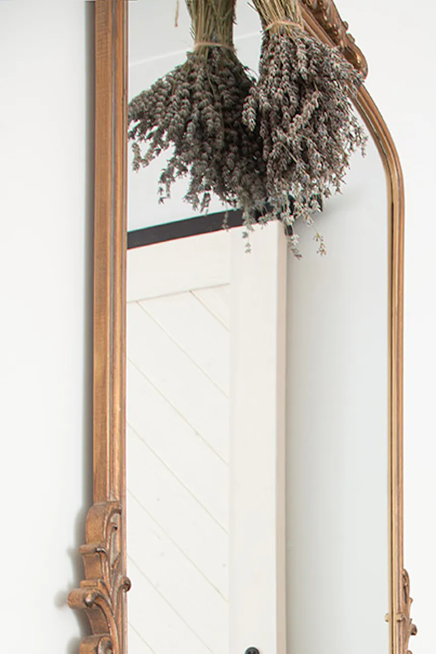 decorative mirror in a wooden frame on the wall above the black piano