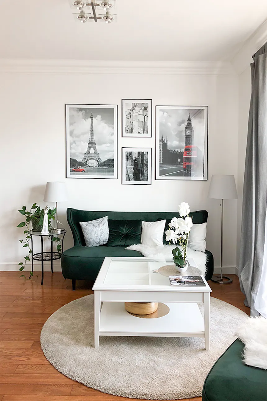 Glamor style interior, green sofa, white living room table, stylized furniture, paintings on the wall