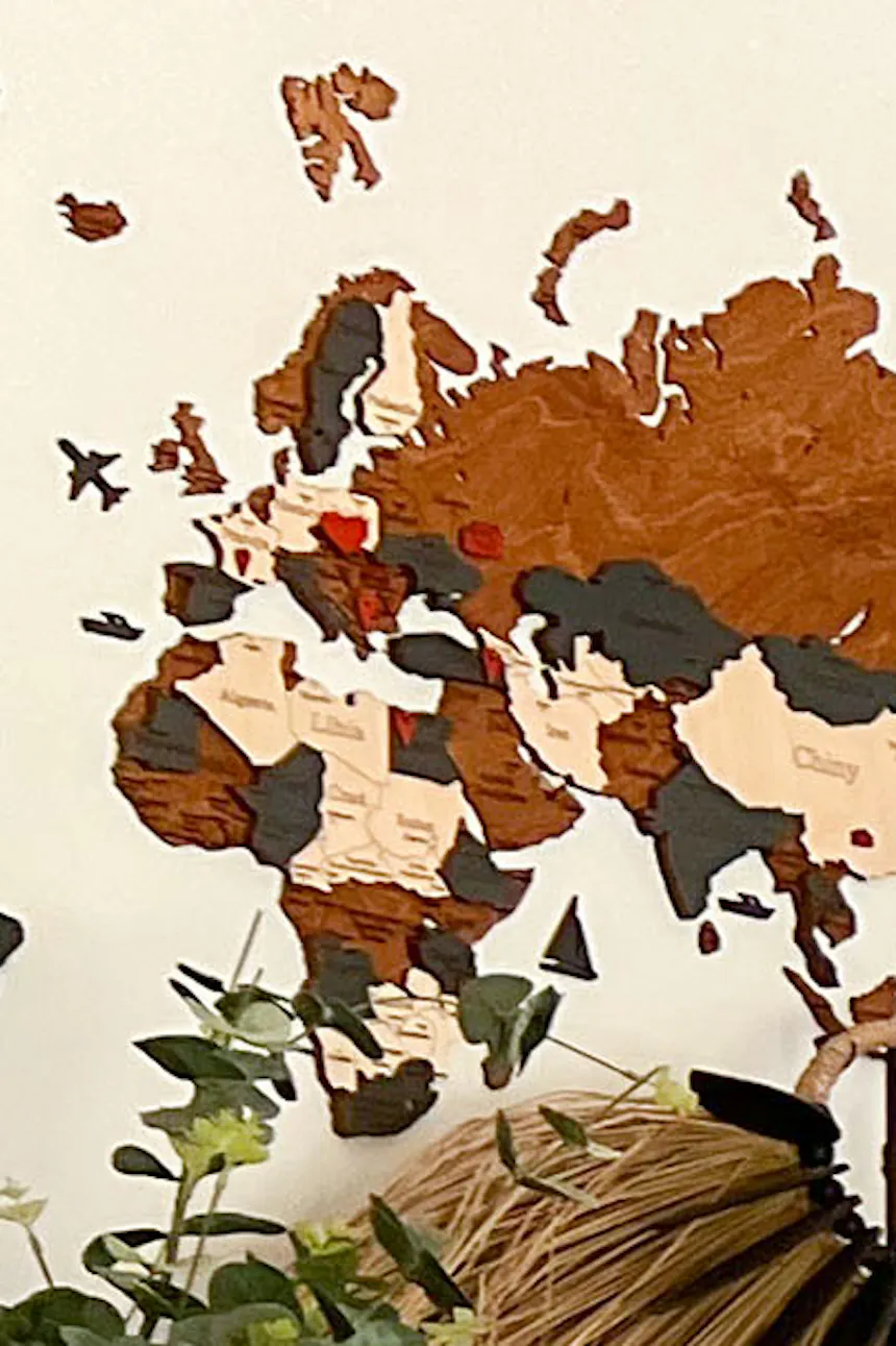 a wooden map of the world on the wall and a decorative fan on the dresser