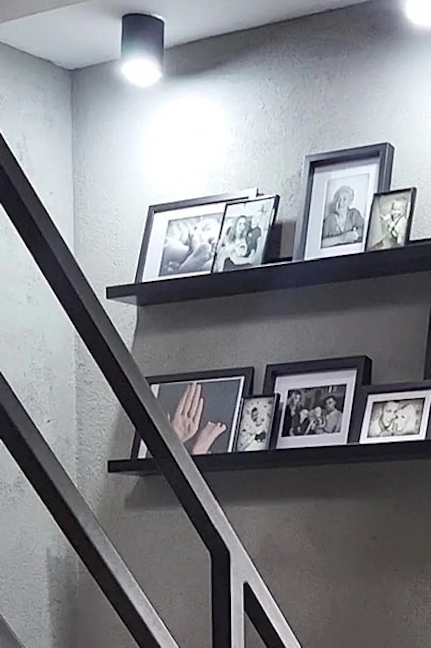 galerie de photos dans des cadres noirs sur un mur de béton gris