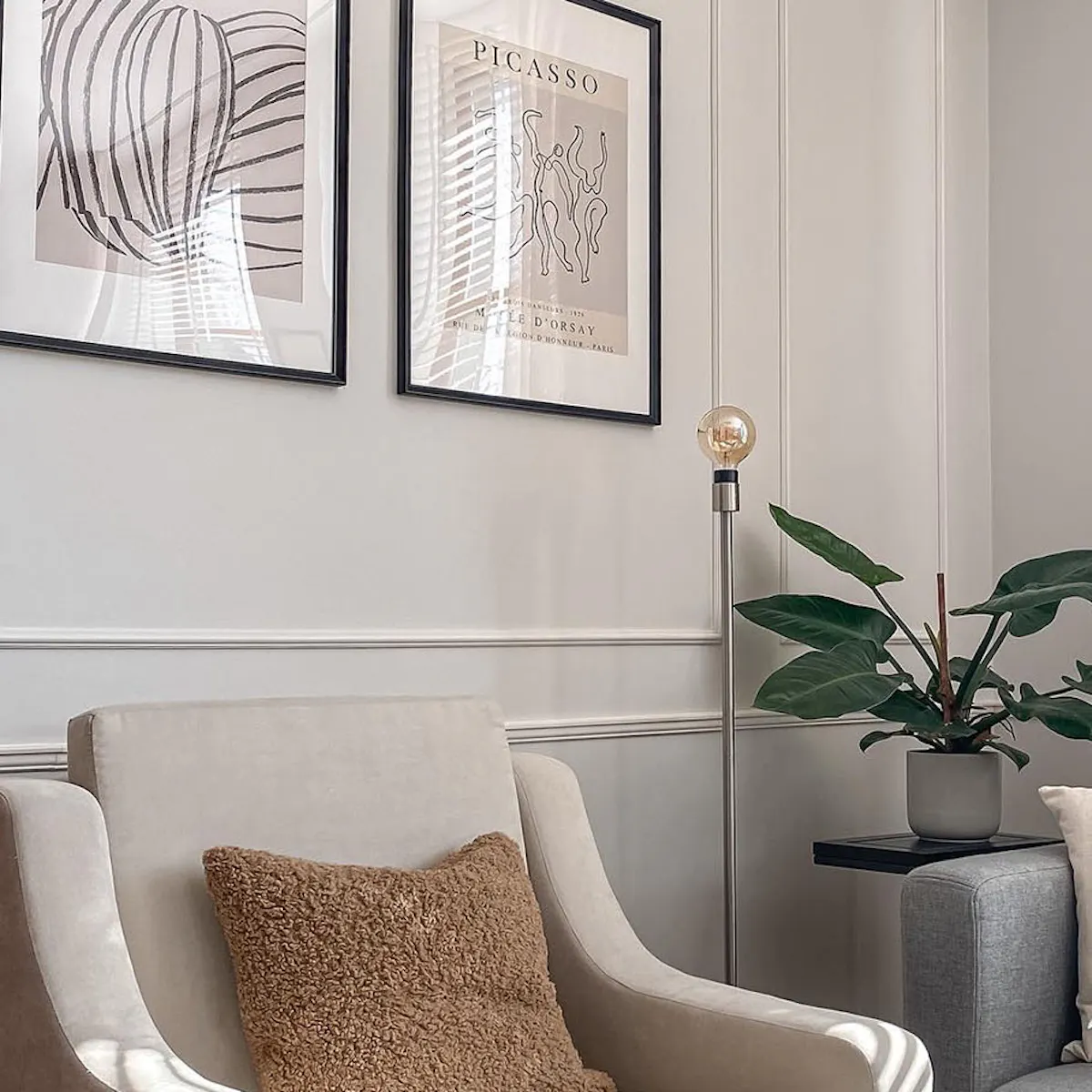 Gray sofa, cream armchair, eclectic living room, wall molding in living room, framed poster on living room wall