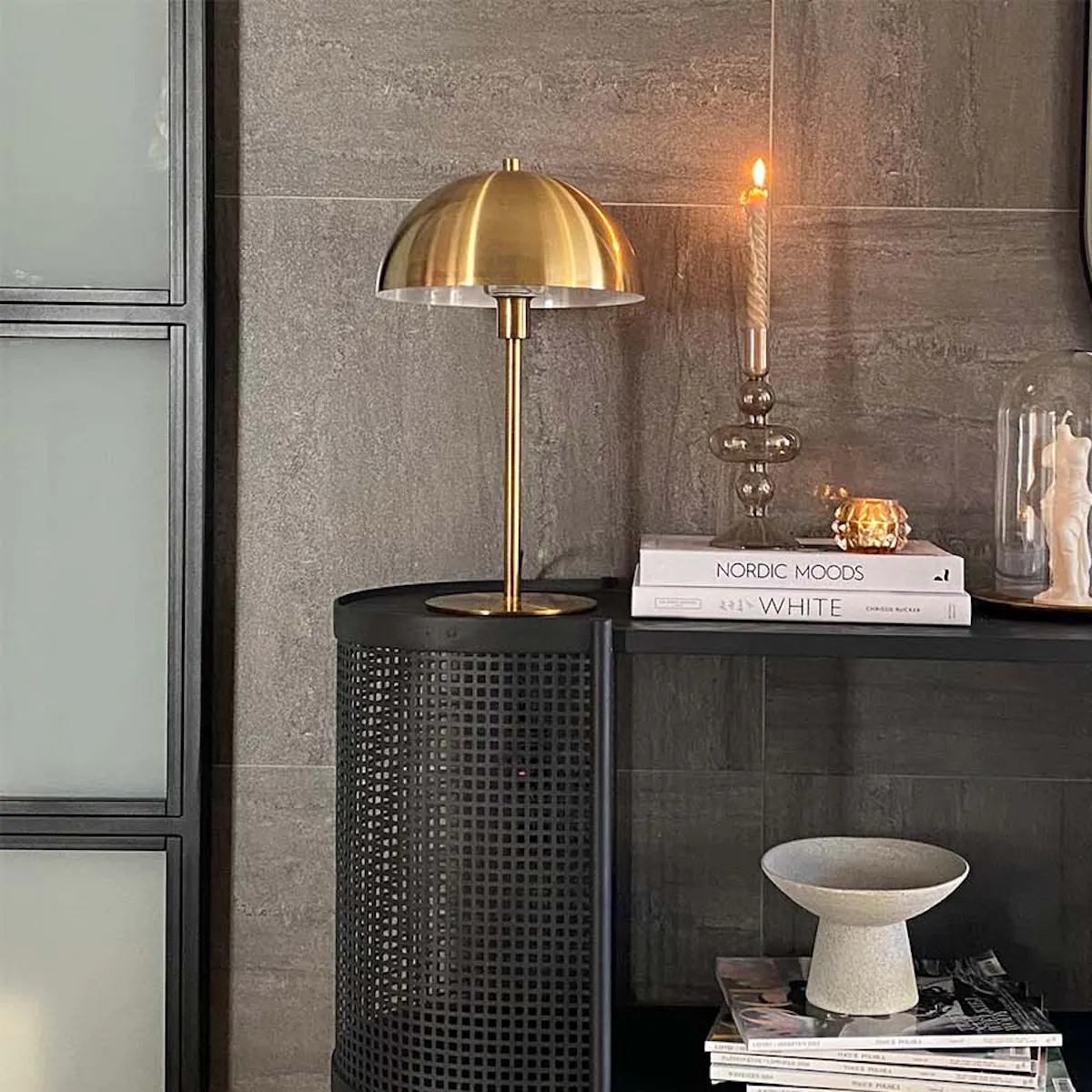 Black decorative console in hallway, graphite tiles on wall, golden lamp on black console, minimalist décor on console