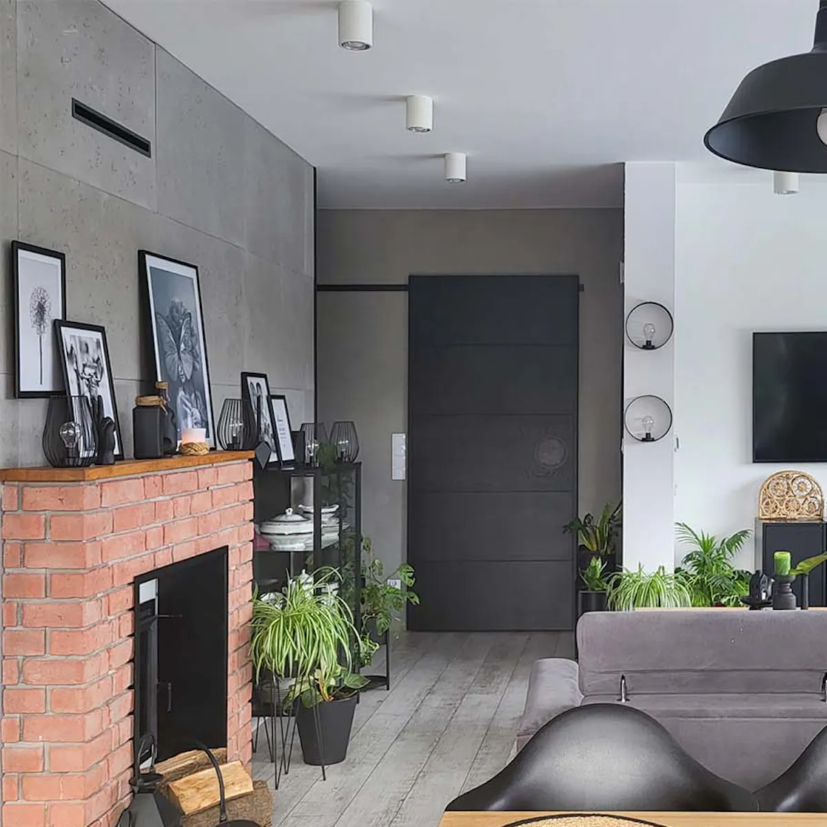 wooden dining table, red brick fireplace and black sliding doors in a living room decorated in gray colors