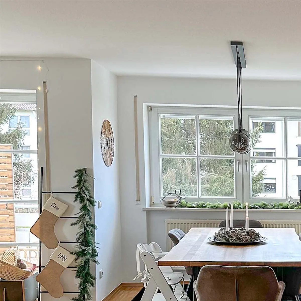 une grande table à manger sur un tapis noir à côté d'une grande fenêtre dans le salon