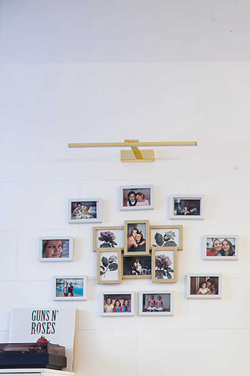photo gallery in wooden frames next to a metal white door with a mirror