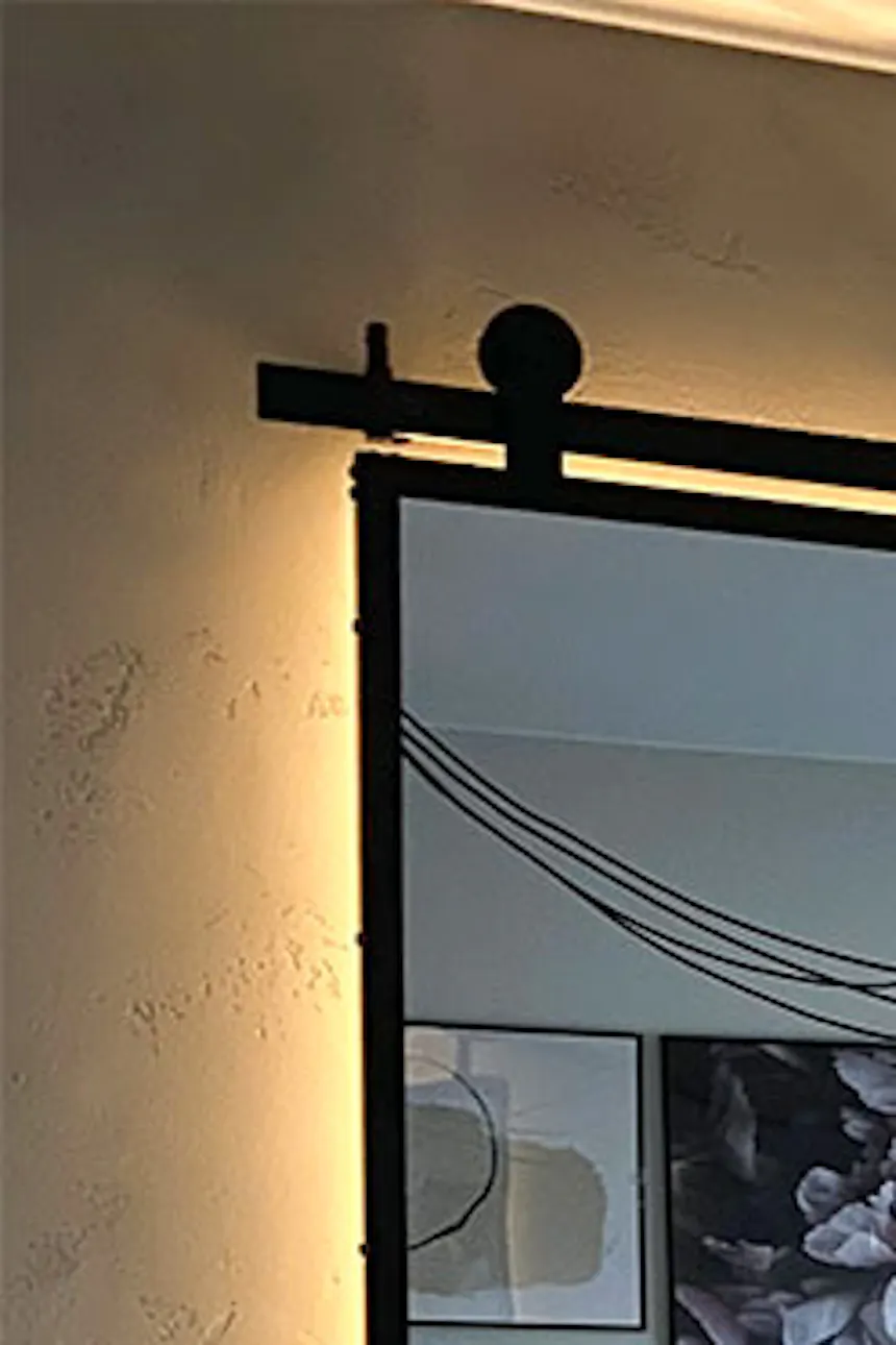 Sliding doors with large mirror in metal frame closing off dressing room in bedroom niche in loft style