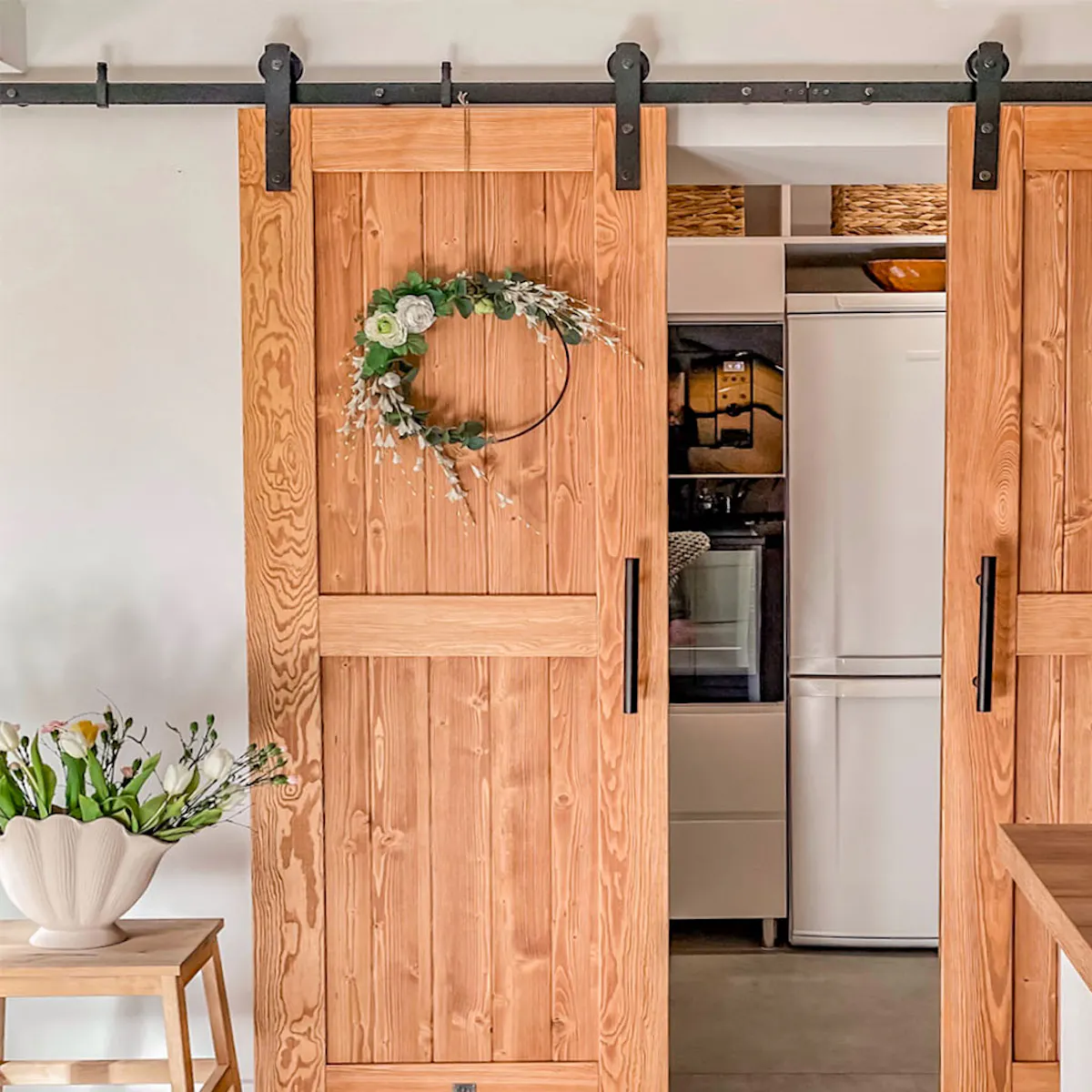 appareils électroménagers cachés dans un renfoncement de cuisine fermé par des doubles portes coulissantes