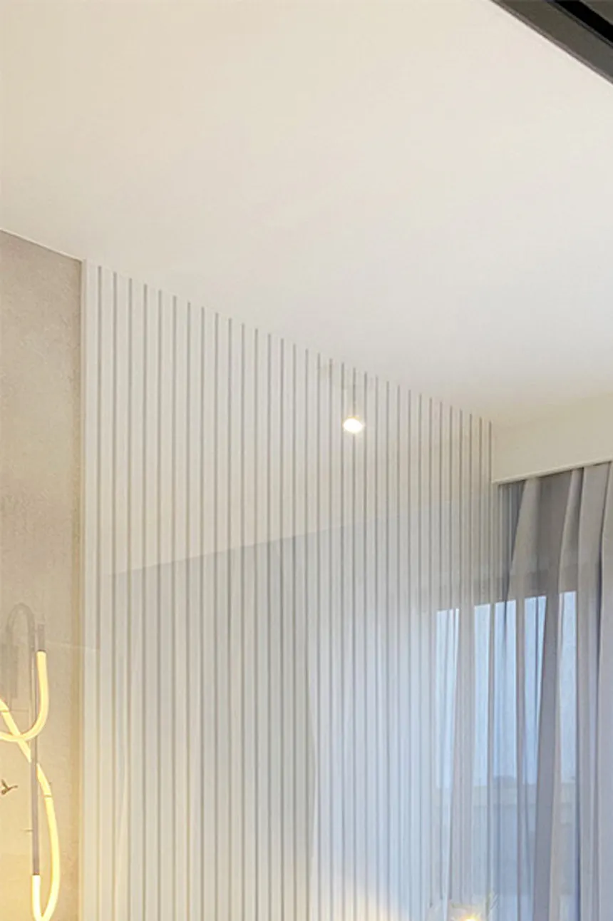 Glass sliding doors with black metal frame separating bedroom from living room, modern apartment