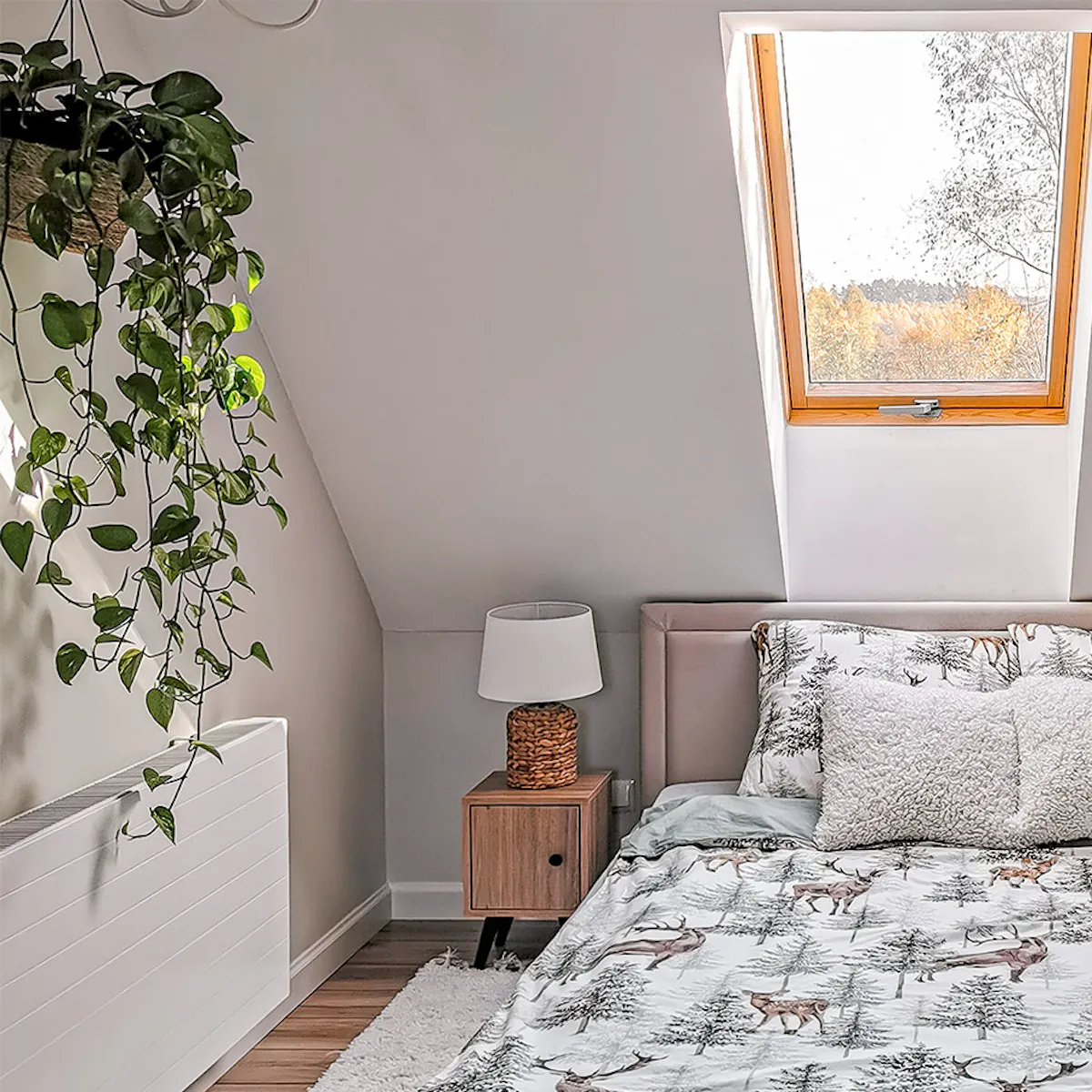 literie aux motifs forestiers sur un lit capitonné avec une tête de lit située sous la lucarne