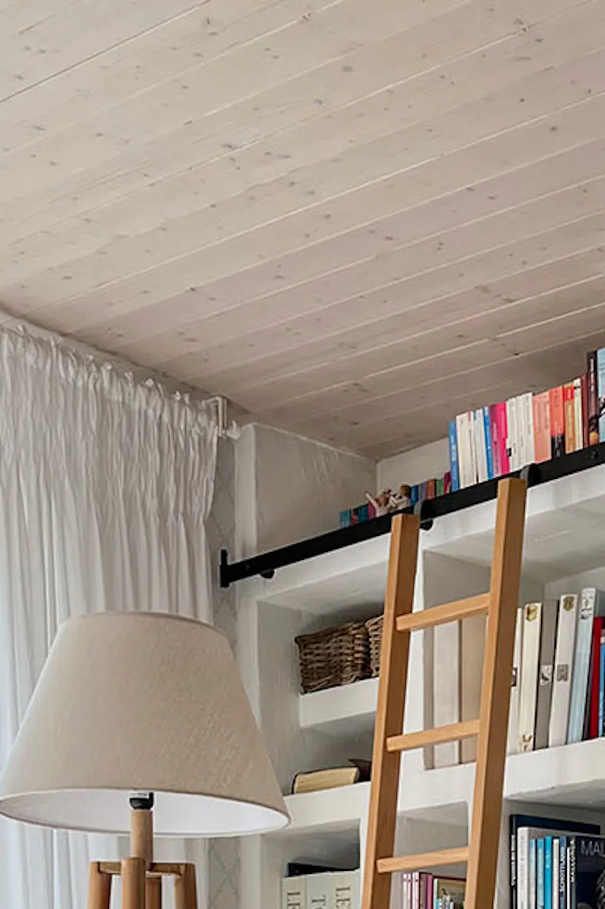 une échelle et une porte coulissante blanche dans l'agencement d'une bibliothèque à domicile dans le salon