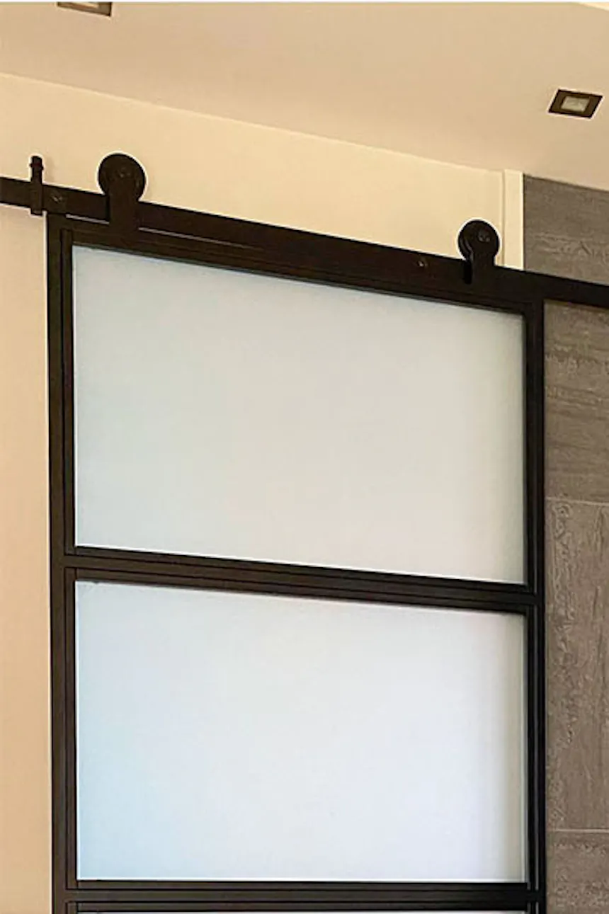 Industrial sliding door for kitchen, glass door between kitchen and hallway, graphite tiles on hallway wall, golden lamp on black console in hallway