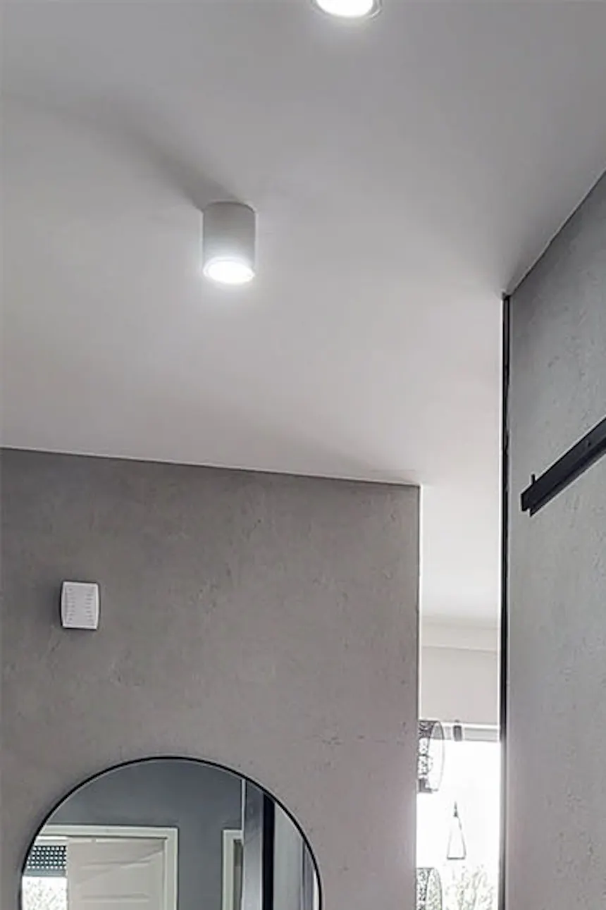 porte coulissante noire à l'entrée de la salle de bain dans le couloir aux murs gris