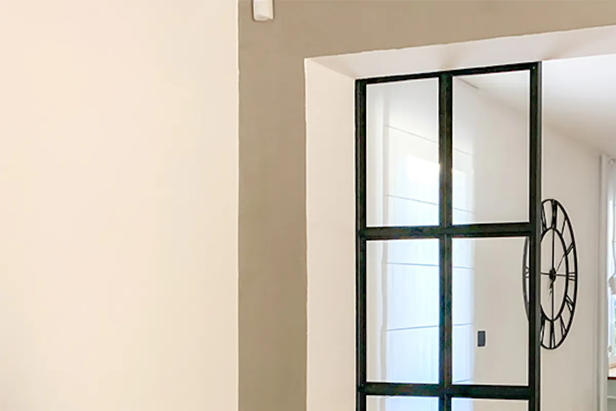 Open living room to dining room, open living room, glass and metal sliding doors, metal glass sliding doors, loft-style doors, industrial pendant lights for dining room, botanical wallpaper, decorative wallpaper, large wooden table, green dining chairs